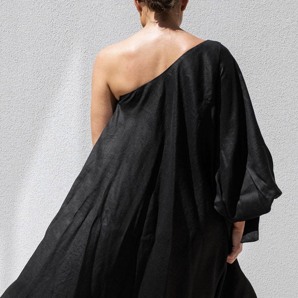 
                      
                        The person wears an Isabella Longginou Black Balloon Sleeve Swing Dress, standing against a light gray wall. Their hair is styled in a bun as they face away from the camera, showcasing the dresss draped elegance by Australian Designed Fashion.
                      
                    